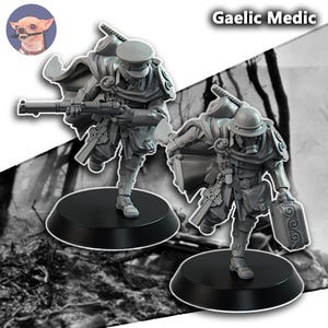 May include: Two grey miniature figurines on black circular bases, labeled Gaelic Medic. One figure holds a rifle, the other a medical bag and gas mask. Both wear military-style uniforms with capes, shoulder armor, and Celtic cross details.