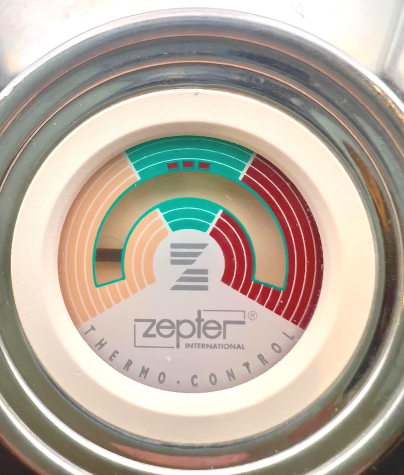 May include: Close-up of a Zepter Thermo Control dial. The dial features a white face with a circular design in shades of green, red, and beige. The text "zepter INTERNATIONAL THERMO.CONTROL" is printed on the dial.