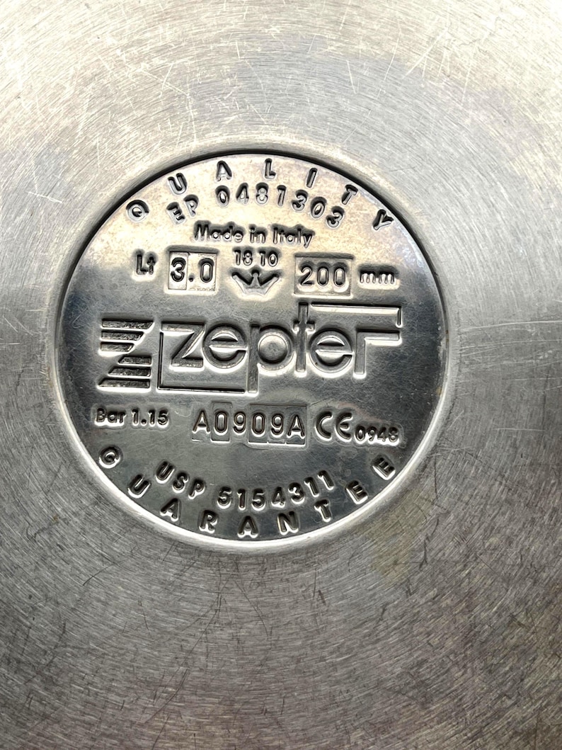 May include: Close-up of a stainless steel Zepter product base. The base features embossed text including "Made in Italy", "3.0 L", and "200 mm". Other text includes "USP 5154311 GUARANTEE".