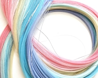 May include: A selection of rainbow-coloured hair extensions. The extensions feature pastel shades of pink, yellow, blue, and purple, with strands of silver tinsel. Each bundle has a black clip for easy attachment. Perfect for adding a splash of colour to any hairstyle.
