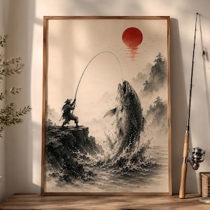 Peut inclure: Illustration encadrée d'un pêcheur en tenue traditionnelle luttant contre un gros poisson, avec un soleil rouge se couchant sur des montagnes brumeuses. L'œuvre est de style japonais Ukiyo-e, avec un cadre en bois.