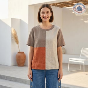 May include: A short-sleeved top featuring a colour-blocked design with a brown upper left panel, a cream right panel, and a burnt orange lower left panel. The garment has a round neckline and a straight hem, paired with blue denim jeans.