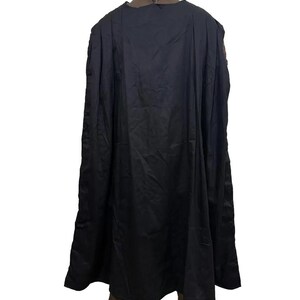 May include: A black cape with a long, flowing design. The cape is draped over a mannequin, showcasing its full length and shape. The fabric appears to be a smooth, matte material.