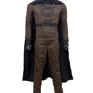 May include: A brown costume with a black cape. The costume includes a long-sleeved jacket with square patches, matching pants, and a black cowl. The cape is attached at the shoulders. The outfit is displayed on a mannequin.