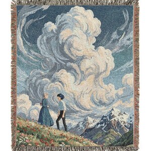 May include: Woven throw blanket featuring a landscape scene with two figures on a flowered hillside, with a backdrop of large clouds and snow-capped mountains. The blanket has a fringed edge and is primarily blue, beige, and green.