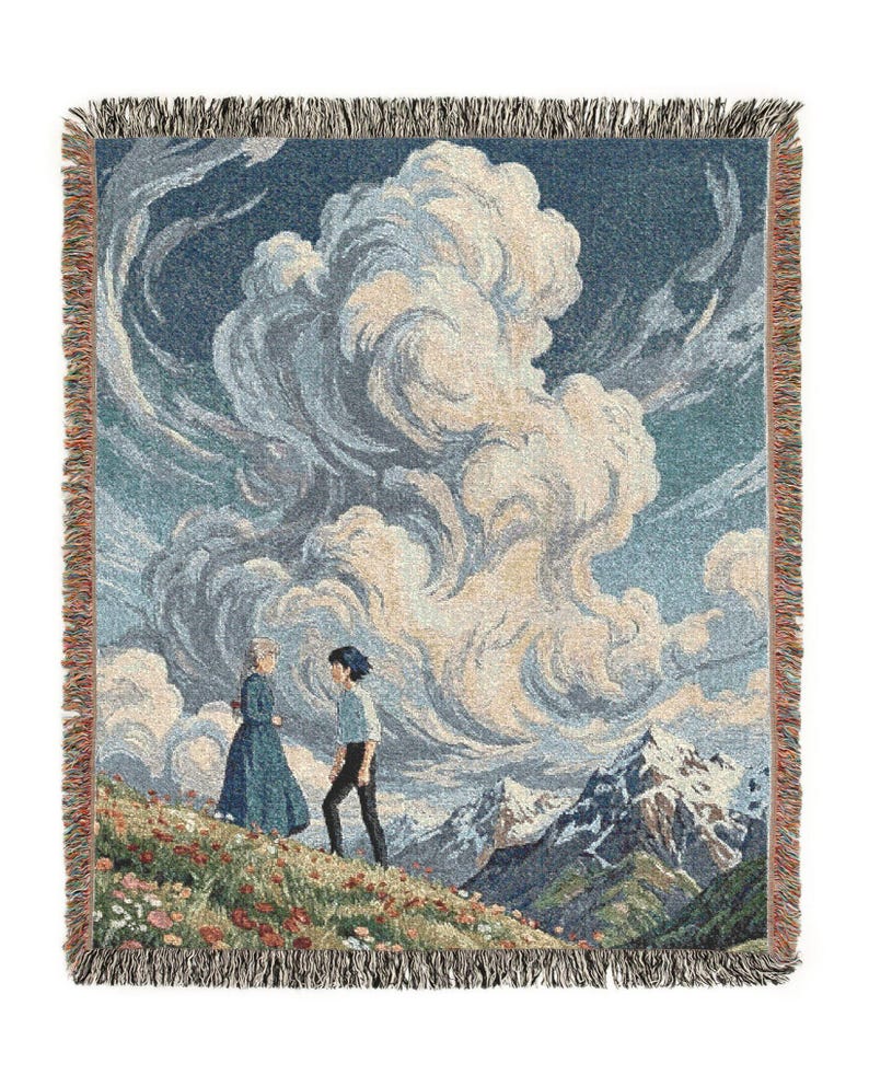 May include: Woven throw blanket featuring a landscape scene with two figures on a flowered hillside, with a backdrop of large clouds and snow-capped mountains. The blanket has a fringed edge and is primarily blue, beige, and green.
