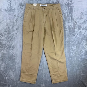 May include: Khaki-coloured Dockers trousers with a button closure and pleats. The trousers have two front pockets and two back pockets. The tag reads "Dockers".