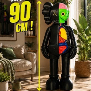 Pode incluir: Uma figura KAWS preta com um design dividido que revela uma cabeça verde, um cérebro rosa e órgãos internos coloridos. Uma seta amarela e texto indicam uma altura de 90 cm. A figura apresenta olhos e mãos em forma de X e está de pé.
