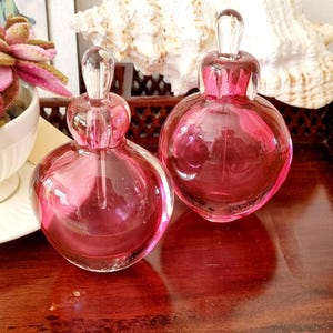 Vintage set van 2 dikke donkerroze glazen parfumflesjes met stopper.
