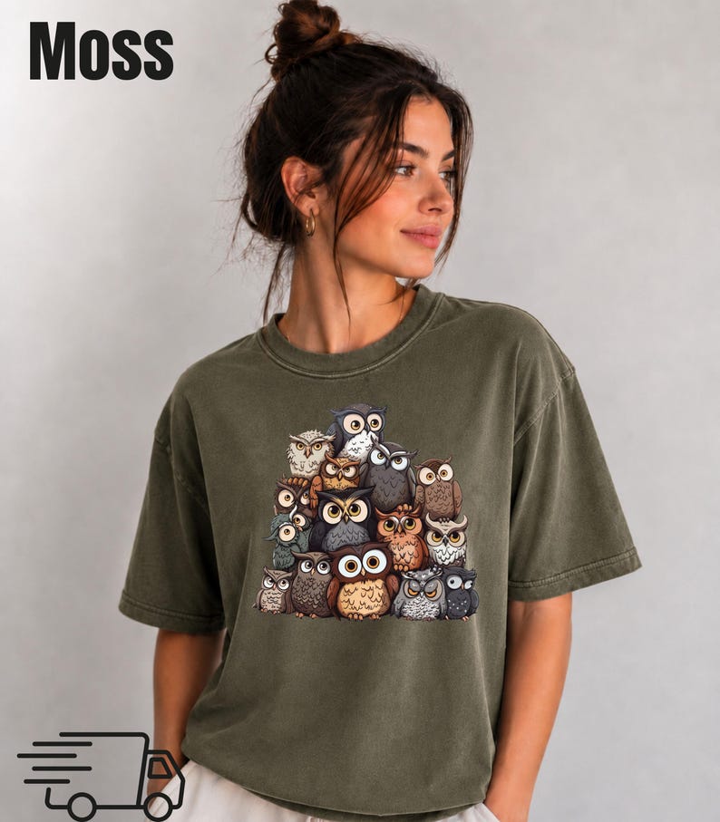 Puede incluir: Una camiseta de manga corta color verde musgo con un estampado gr&aacute;fico de un grupo de varios b&uacute;hos en tonos marrones, grises y blancos. La palabra Moss est&aacute; impresa en negro en la esquina superior izquierda y un icono de cami&oacute;n negro abajo.