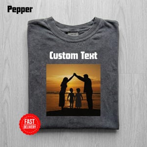 Könnte beinhalten: Dunkelgraues T-Shirt mit einer Familiensilhouetten-Grafik bei Sonnenuntergang. Das Shirt trägt den Text "Custom Text" in weißen Blockbuchstaben. Ein roter "Fast Delivery"-Aufkleber befindet sich in der unteren linken Ecke.