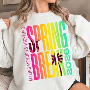 May include: White sweatshirt with the words "SPRING BREAK 2026" in a colorful gradient font. The text "MAKING MEMORIES TOGETHER" is printed vertically on the left side. Palm tree graphics are incorporated into the design.