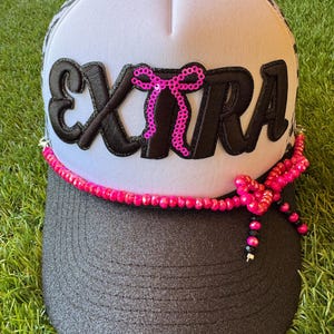 EXTRA embroidered word patch with hot pink sequined bow on a glitter brim custom trucker