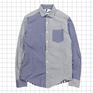 Può includere: Una camicia a maniche lunghe con un design unico. La camicia è divisa verticalmente, con un motivo a quadretti blu e bianco sul lato sinistro e un motivo a righe blu e bianco sul lato destro. Ha una tasca sul petto e un colletto button-down.