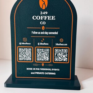 May include: An arched dark green sign with orange trim featuring the text 249 COFFEE CO, three QR codes, social media handles, and the text BOOK US FOR WEDDINGS, EVENTS and PRIVATE CATERING. The sign includes coffee bean icons and lines.