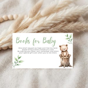 Può includere: Biglietto d'invito per baby shower con la scritta "Books for Baby" in verde. Il biglietto presenta un'illustrazione ad acquerello di un orsacchiotto seduto su un ceppo d'albero. Il biglietto include anche una richiesta di portare un libro invece di un biglietto.