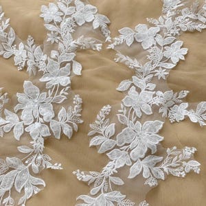 Peut inclure: Garniture de dentelle florale blanche avec des paillettes, idéale pour ajouter une touche d'élégance aux robes de mariée, aux accessoires de mariée ou à d'autres projets d'artisanat.