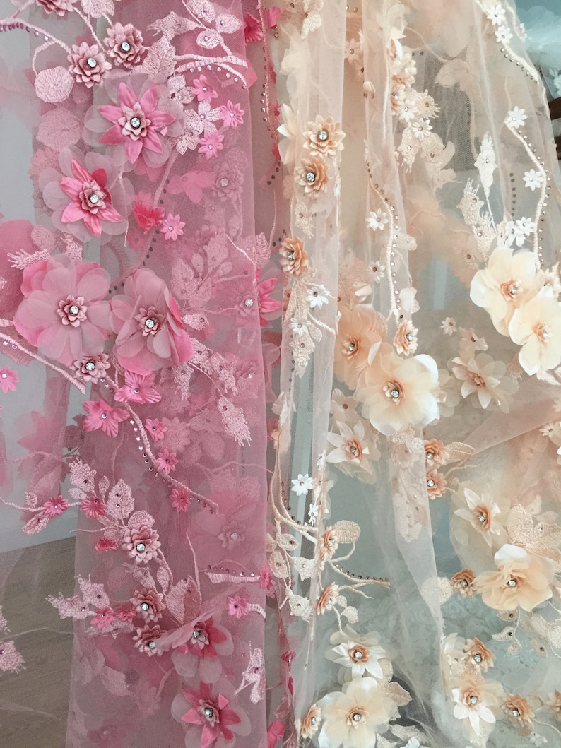 Puede incluir: Dos piezas de tela transparente con bordado floral 3D. La tela de la izquierda es rosa y la tela de la derecha es beige.