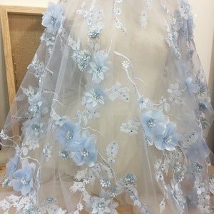 Puede incluir: Tela de encaje floral azul claro con flores 3D y adornos brillantes. La tela es transparente y delicada, perfecta para agregar un toque de elegancia a cualquier proyecto.