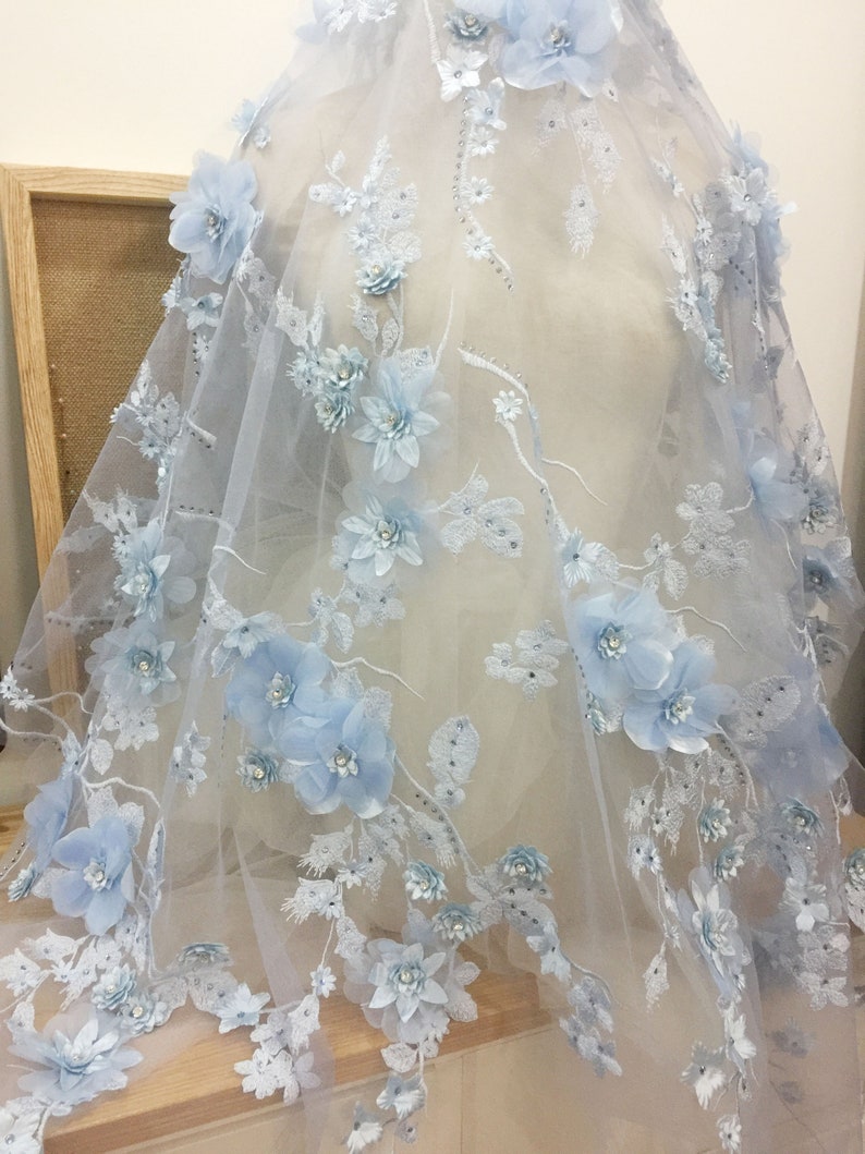 Puede incluir: Tela de encaje floral azul claro con flores 3D y adornos brillantes. La tela es transparente y delicada, perfecta para agregar un toque de elegancia a cualquier proyecto.