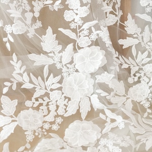 May include: White floral lace fabric with a delicate pattern of flowers and leaves. The lace is on a sheer mesh background.