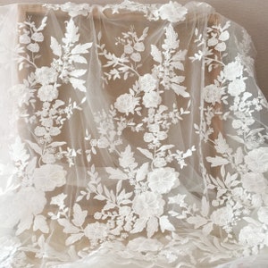 May include: White floral lace fabric with a delicate pattern of flowers and leaves. The lace is on a sheer mesh background.