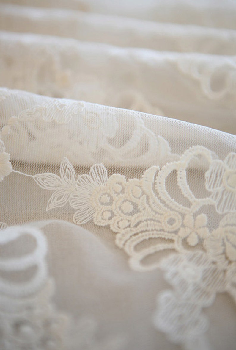 Puede incluir: Tela de encaje blanca con un delicado patr&oacute;n floral. La tela es suave y transparente, con un ligero brillo.