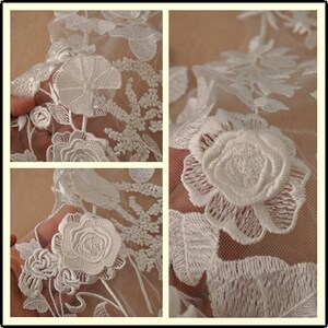 May include: White floral lace fabric with a delicate, embroidered design. The fabric features a repeating pattern of roses and leaves.