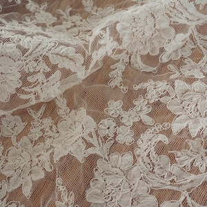 May include: White lace fabric with a floral pattern. The lace is delicate and intricate, with a soft, flowing texture.