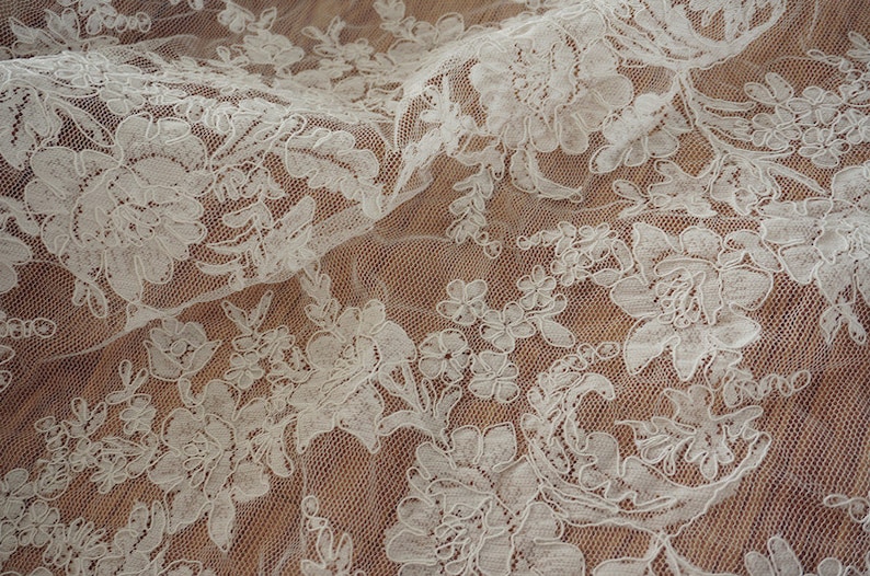 May include: White lace fabric with a floral pattern. The lace is delicate and intricate, with a soft, flowing texture.
