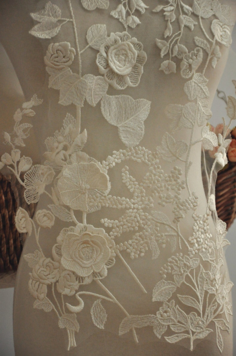 May include: Ivory floral lace applique with delicate flowers and leaves. The lace is on a sheer mesh background.