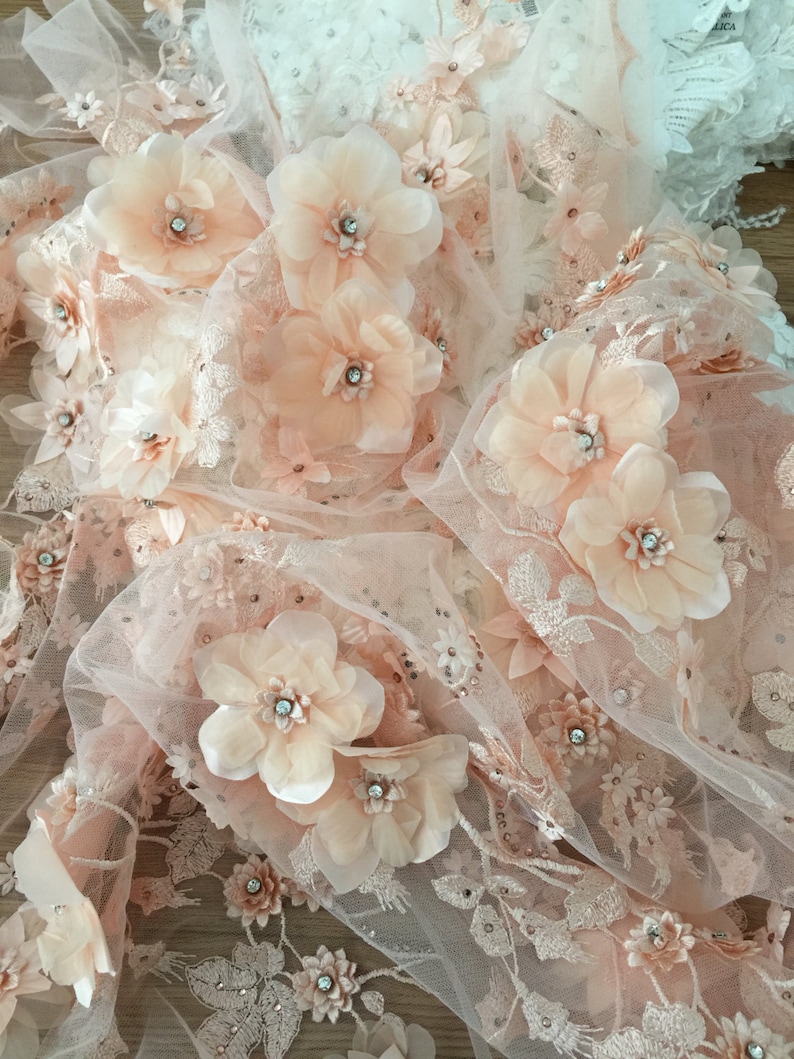 Puede incluir: Tela de encaje floral de color melocot&oacute;n con flores 3D y pedrer&iacute;a. La tela es transparente y delicada, con un tacto suave y rom&aacute;ntico.