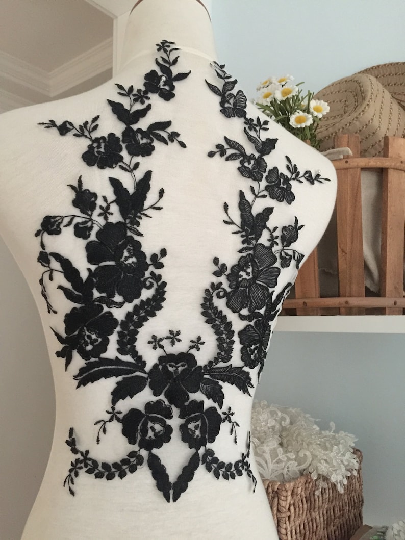 May include: Black floral lace applique for sewing or crafting. The lace features delicate flowers and leaves on a sheer mesh background.