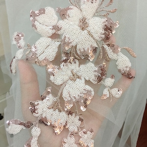 May include: White and rose gold floral embroidery with sequins on a sheer mesh fabric.