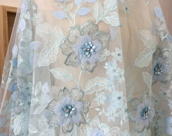 Puede incluir: Tela de encaje floral azul claro con flores y hojas en 3D. La tela tiene una textura delicada y aireada, ideal para añadir un toque de elegancia a cualquier proyecto.