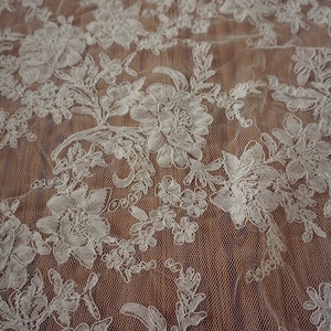 May include: White floral lace fabric with a delicate pattern. The lace is on a sheer mesh background.