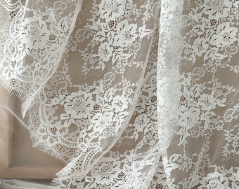 May include: White lace fabric with a floral pattern. The lace has a scalloped edge.