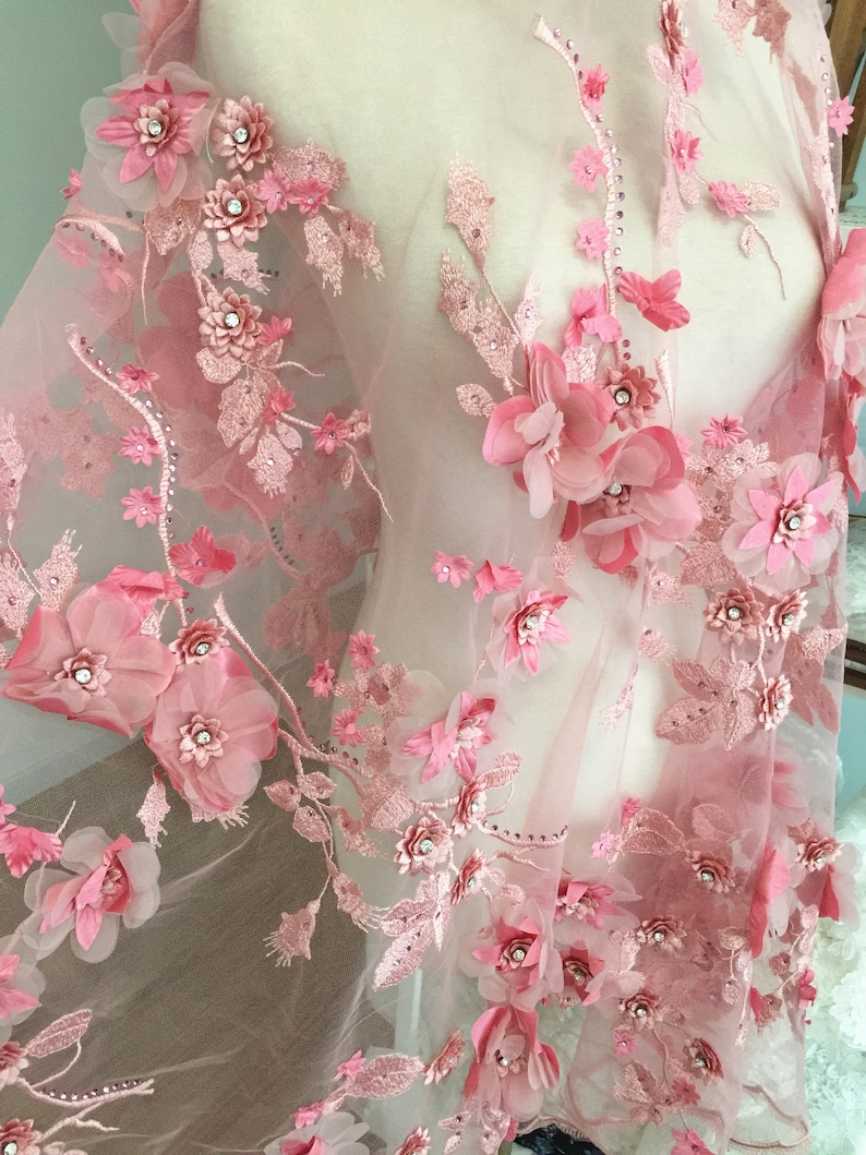 Puede incluir: Tela de encaje floral rosa con flores 3D y pedrer&iacute;a. La tela es transparente y delicada, con un aspecto suave y femenino.