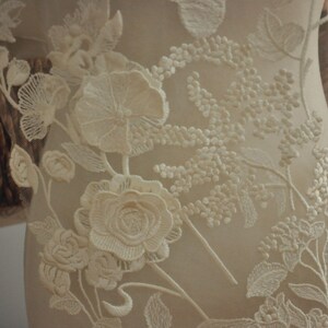 May include: White floral lace fabric with delicate embroidery. The lace features intricate floral designs with a raised texture.