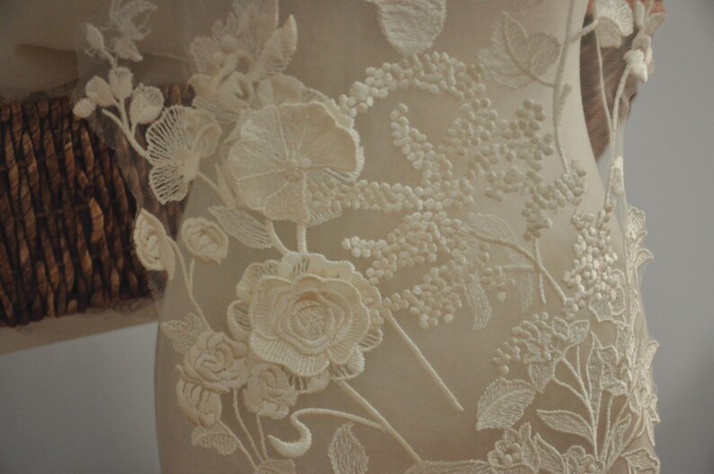 May include: White floral lace fabric with delicate embroidery. The lace features intricate floral designs with a raised texture.