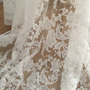 May include: White lace fabric with a floral pattern. The lace is delicate and intricate, with a soft, flowing texture.