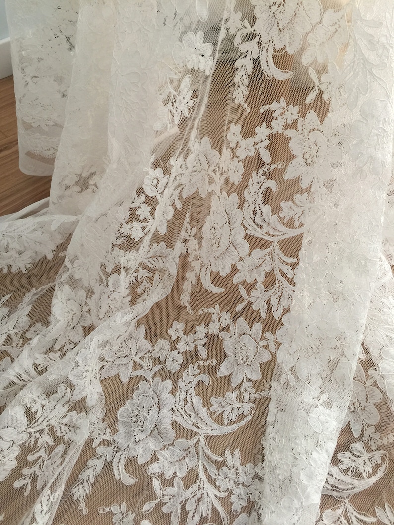 May include: White lace fabric with a floral pattern. The lace is delicate and intricate, with a soft, flowing texture.