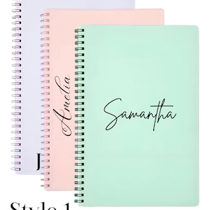 May include: Three spiral-bound notebooks in pastel shades: lavender, peach, and mint green. The mint green notebook has the name "Samantha" in black script. The peach notebook has the name "Amelia" in black script. The lavender notebook has the letter "J" in black script. The text "Style 1" is at the bottom.