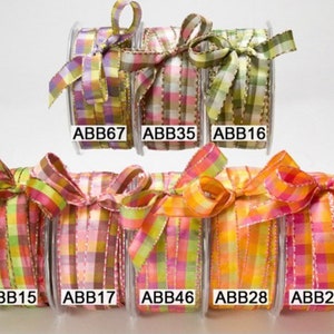 May include: A collection of colorful plaid ribbons on spools, each tied into a bow. The ribbons feature a variety of colors, including pink, green, yellow, and orange. Each spool has a unique product code, such as ABB67, ABB35, and ABB16.