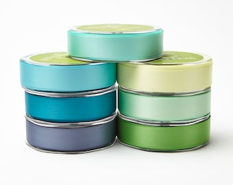 May include: A stack of eight spools of satin ribbon in various shades of blue, green, and yellow. The ribbon is wound around the spools and is ready to be used for crafting or decorating.
