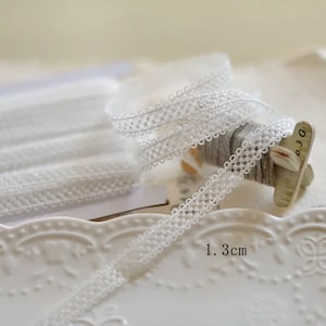 May include: White elastic lace trim with a delicate, intricate pattern. The trim is 1.3 inches wide.