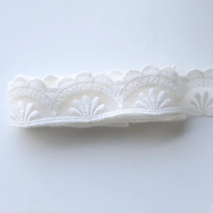 May include: White lace trim with a scalloped edge and a delicate floral pattern.
