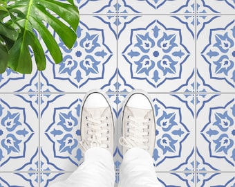 May include: A pair of white canvas shoes with blue laces stand on a blue and white patterned tile floor. The floor is made of square tiles with a repeating geometric design.