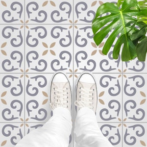May include: A pair of white canvas shoes with black laces stand on a white tiled floor with a gray and brown patterned design. A green leafy plant is in the background.