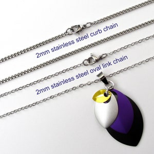 K&ouml;nnte beinhalten: Zwei Edelstahlketten, eine Gliederkette und eine ovale Gliederkette, beide 2 mm breit, mit einem Anh&auml;nger mit drei &uuml;bereinanderliegenden Bl&auml;ttern in Schwarz, Silber und Lila mit einem gelben Akzent.